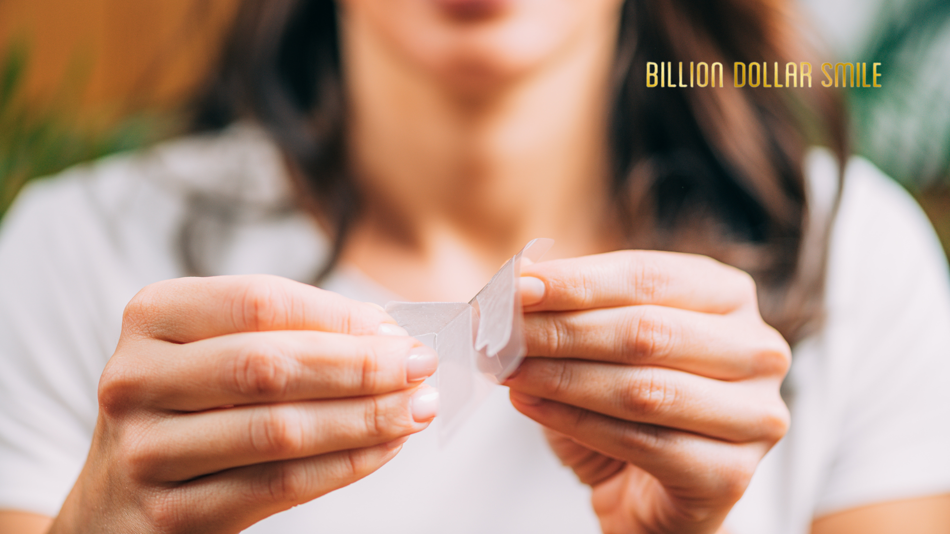An image of someone using the Billion Dollar Smile teeth whitening strips